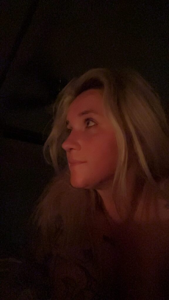 Nikyla in profile, lit warmly against darkness.