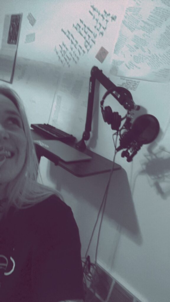 Nikyla in her recording corner, microphone and headphones beside her.