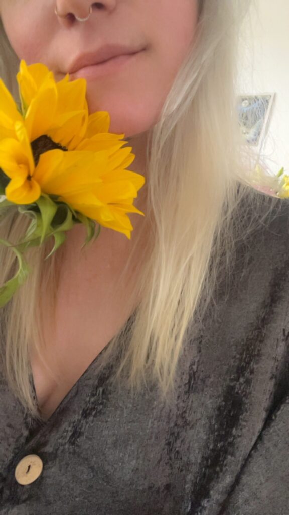 A sunflower held up over Nikyla's face.