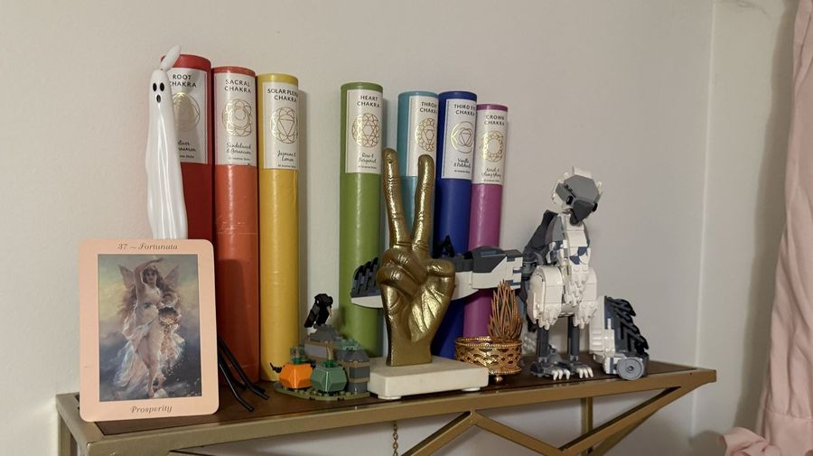 A gold shelf of chakra incense with a plastic ghost, a gold peace-sign hand and a LEGO creature.