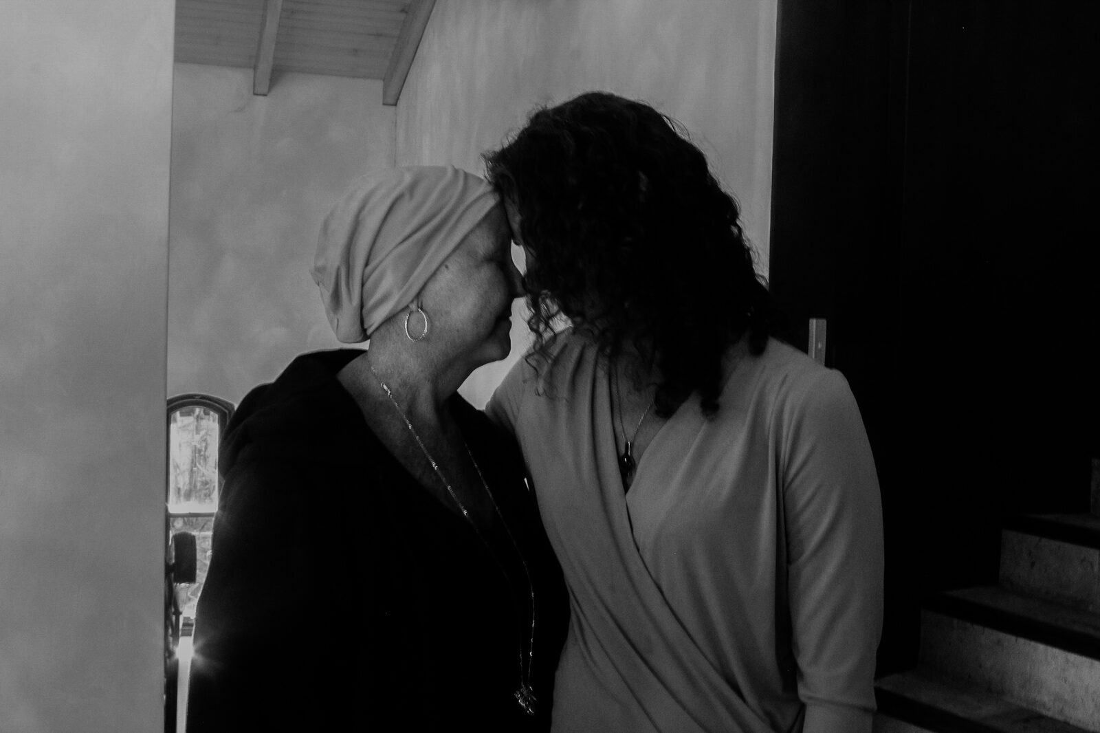Black-and-white photograph of two women resting their foreheads together.